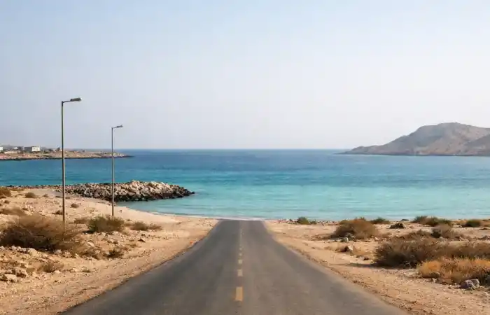 נוף שקט של חוף באי דלמה באבו דאבי, מים רגועים וכביש ריק ליד הים