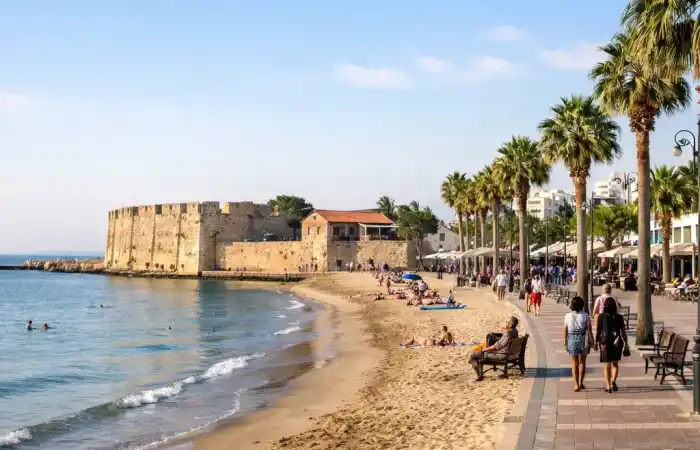 טיילת פיניקודס וחוף לרנקה בקפריסין עם ים שקט, דקלים ומבצר היסטורי ברקע