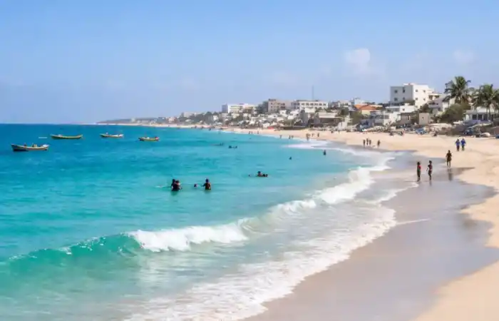 נוף של חוף לידו במוגדישו, סומליה, עם ים כחול, חול בהיר ואנשים על קו החוף
